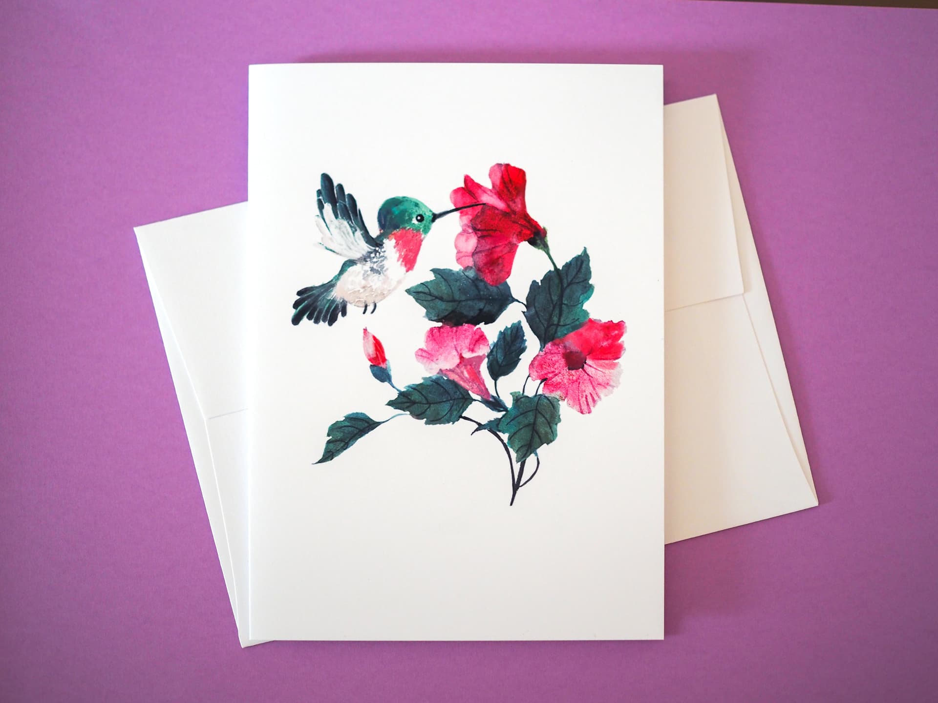 Greeting card with a hummingbird and flowers design on a purple background