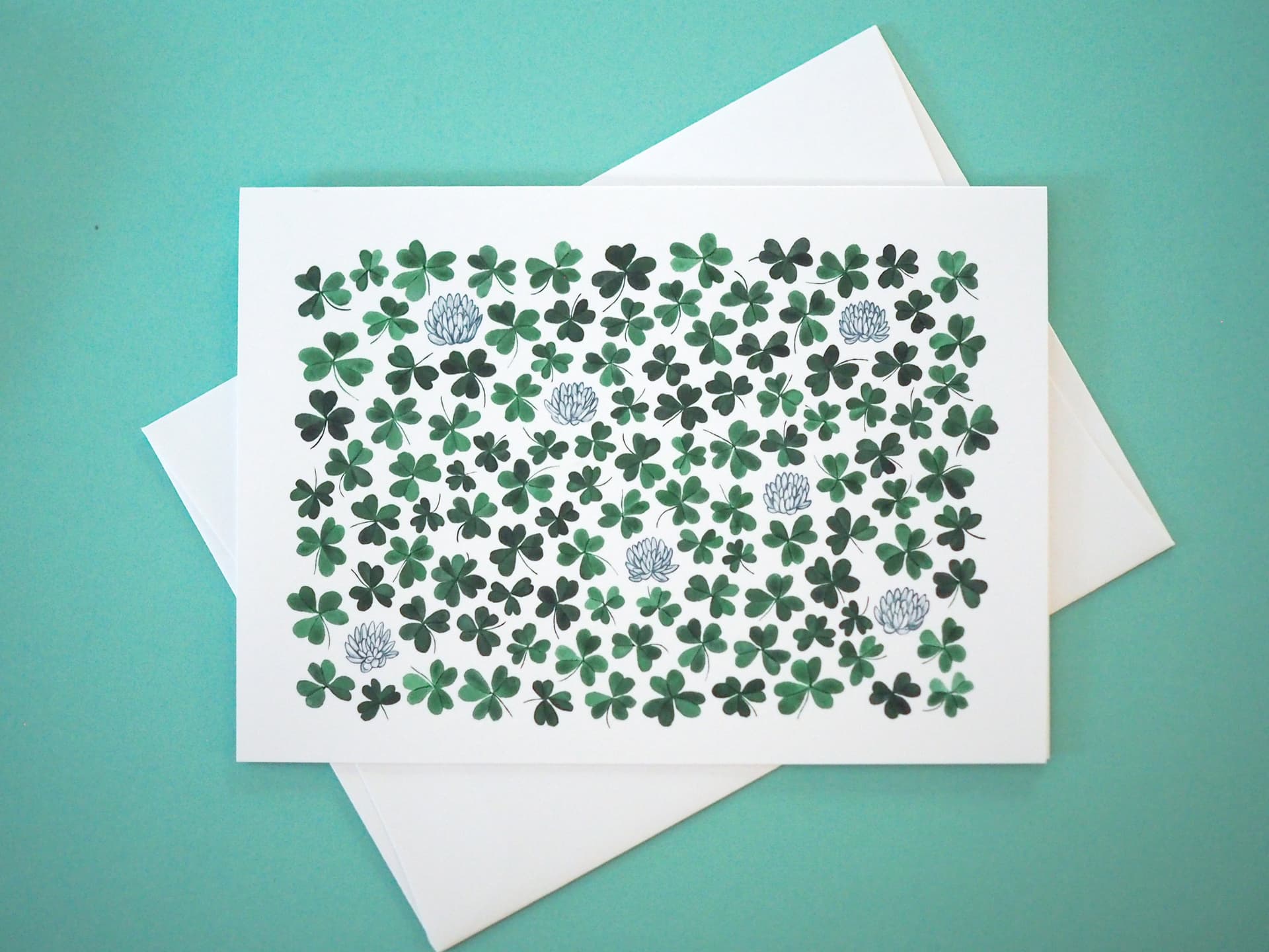 Card with green shamrock pattern on a white envelope against a teal background