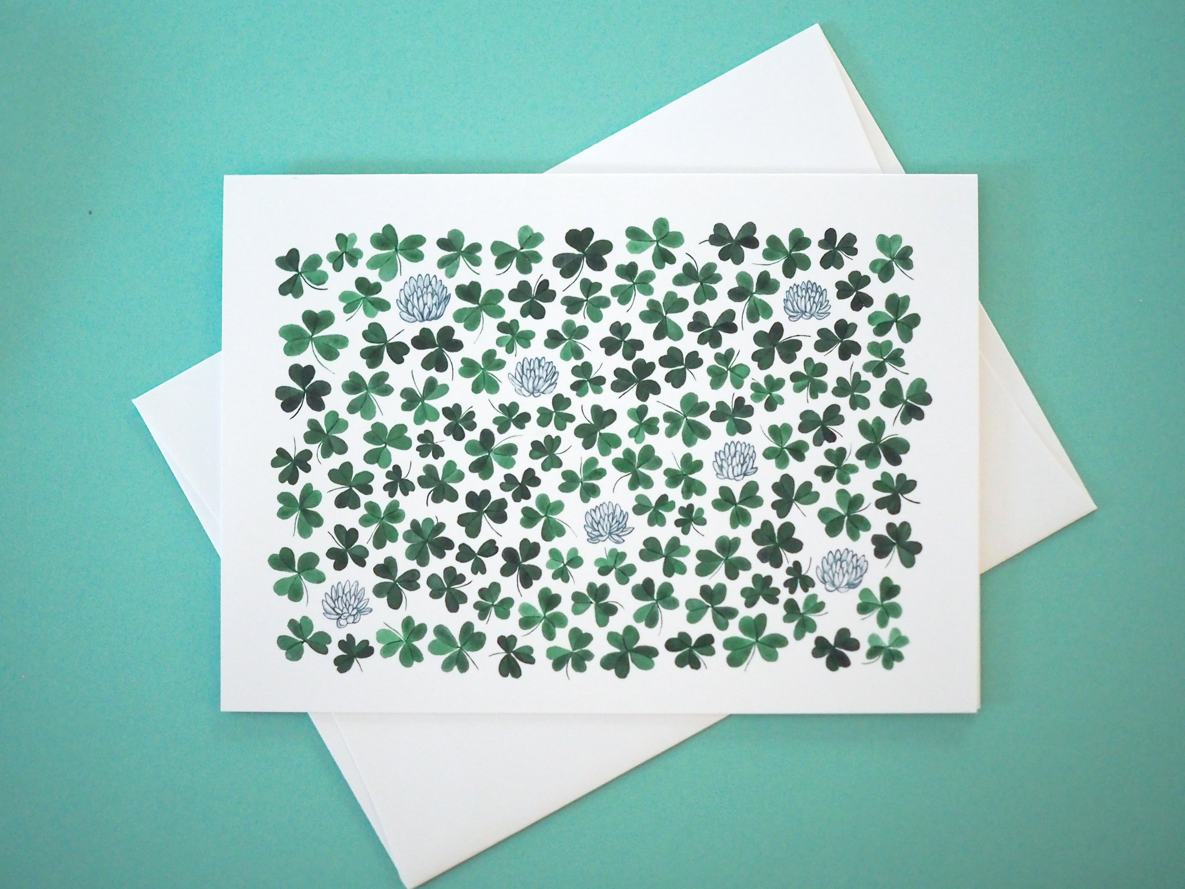 Card with green shamrock pattern on a white envelope against a teal background