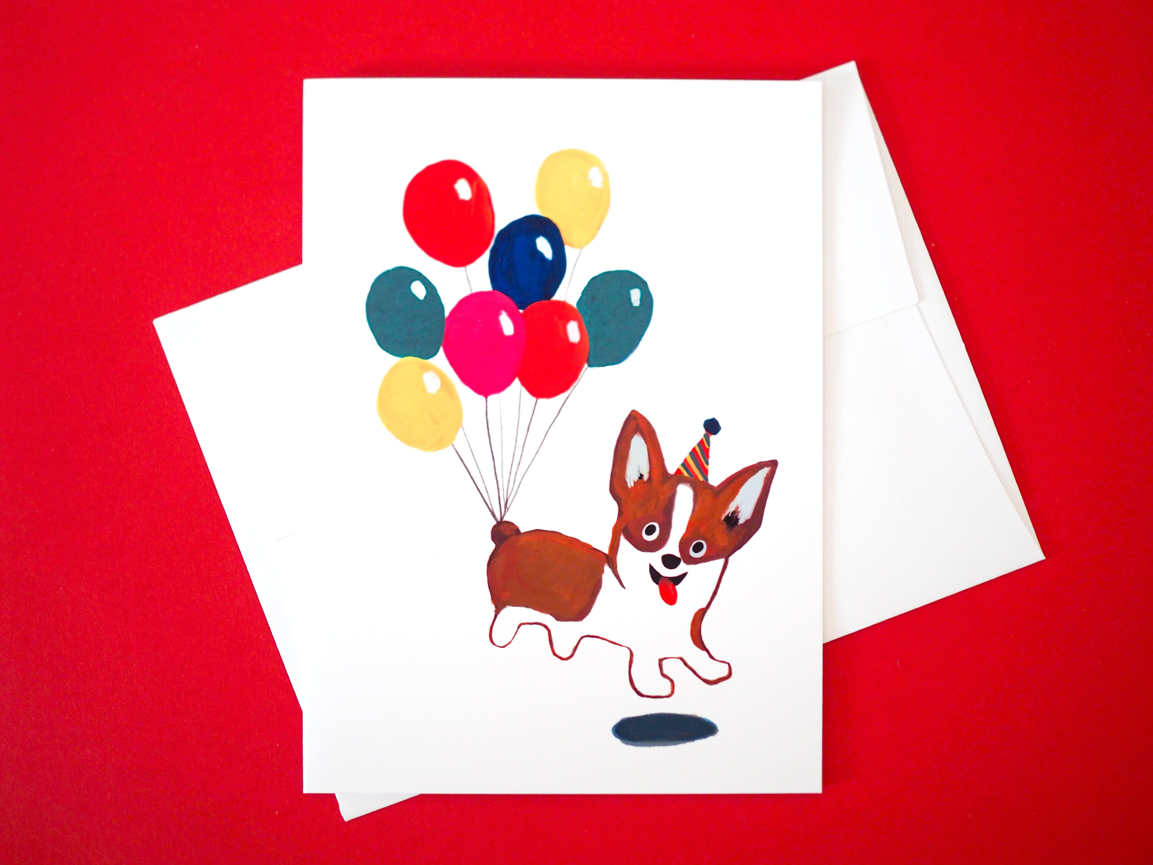 Card with a corgi floating on balloons on a red background