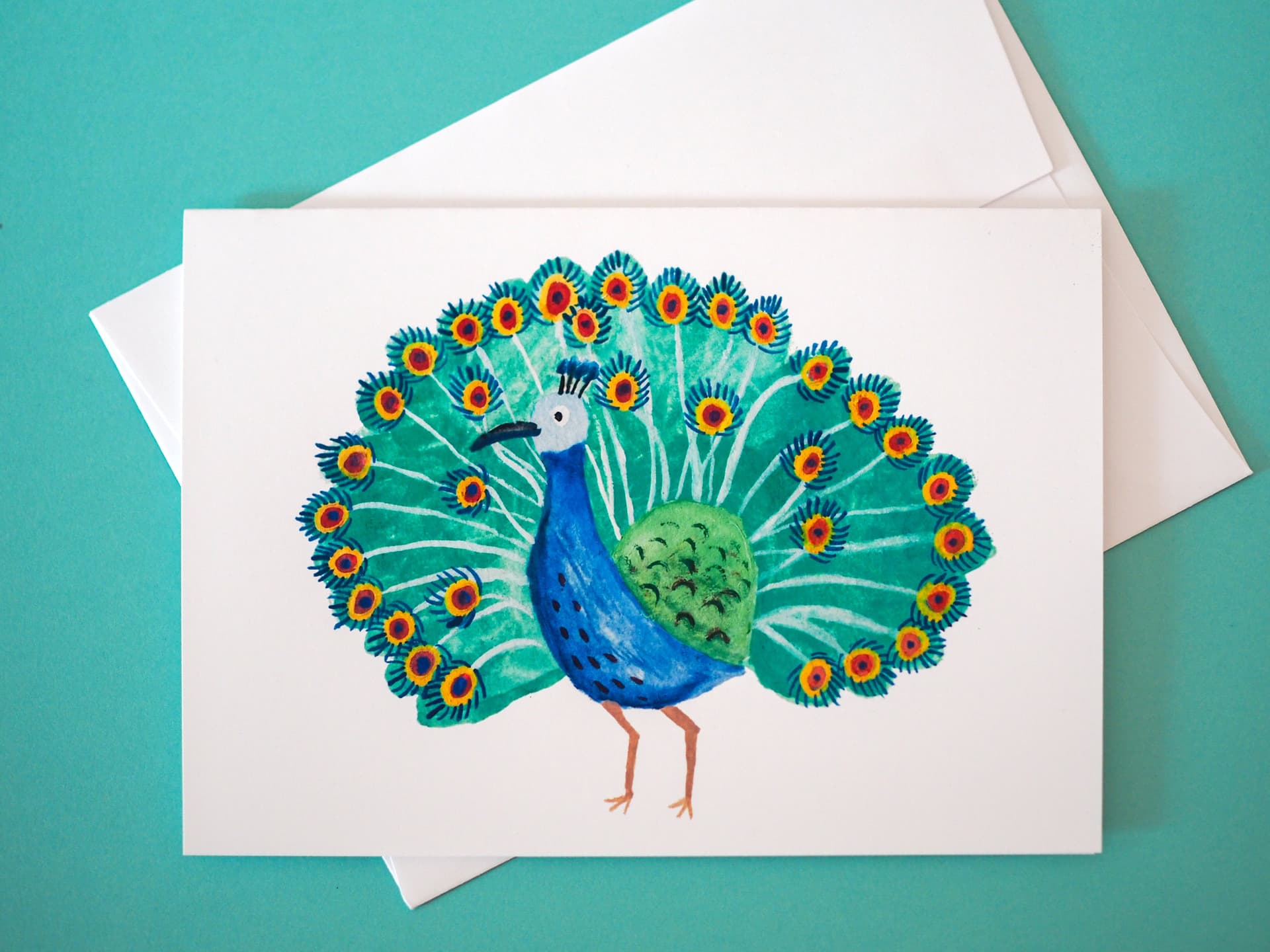 Greeting card with a peacock illustration on a teal background