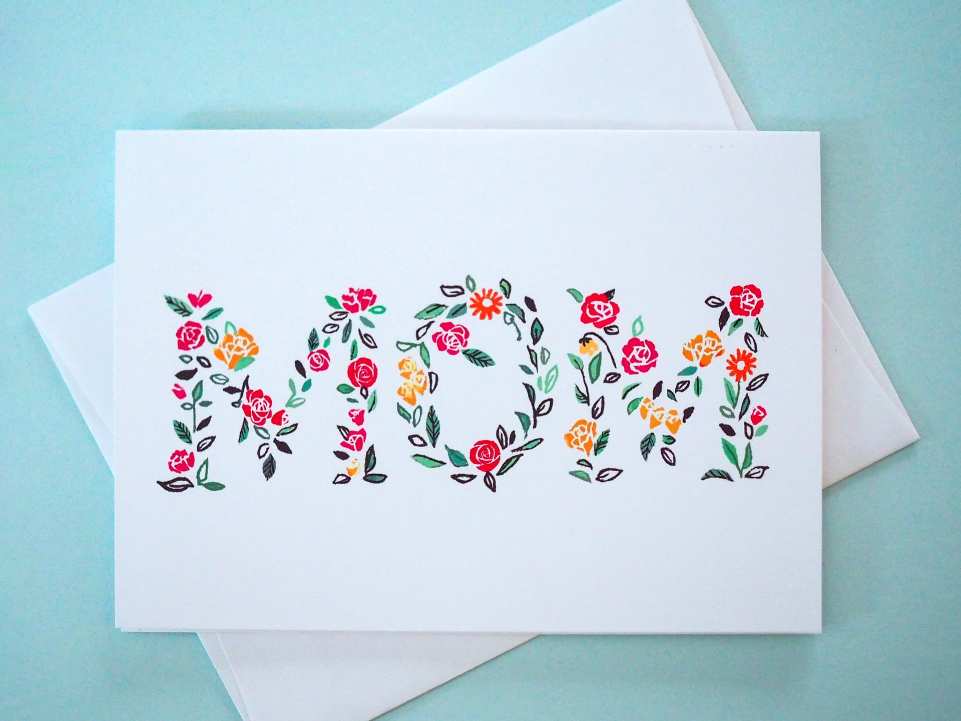 Greeting card with floral letters spelling 'mom' on a light blue background
