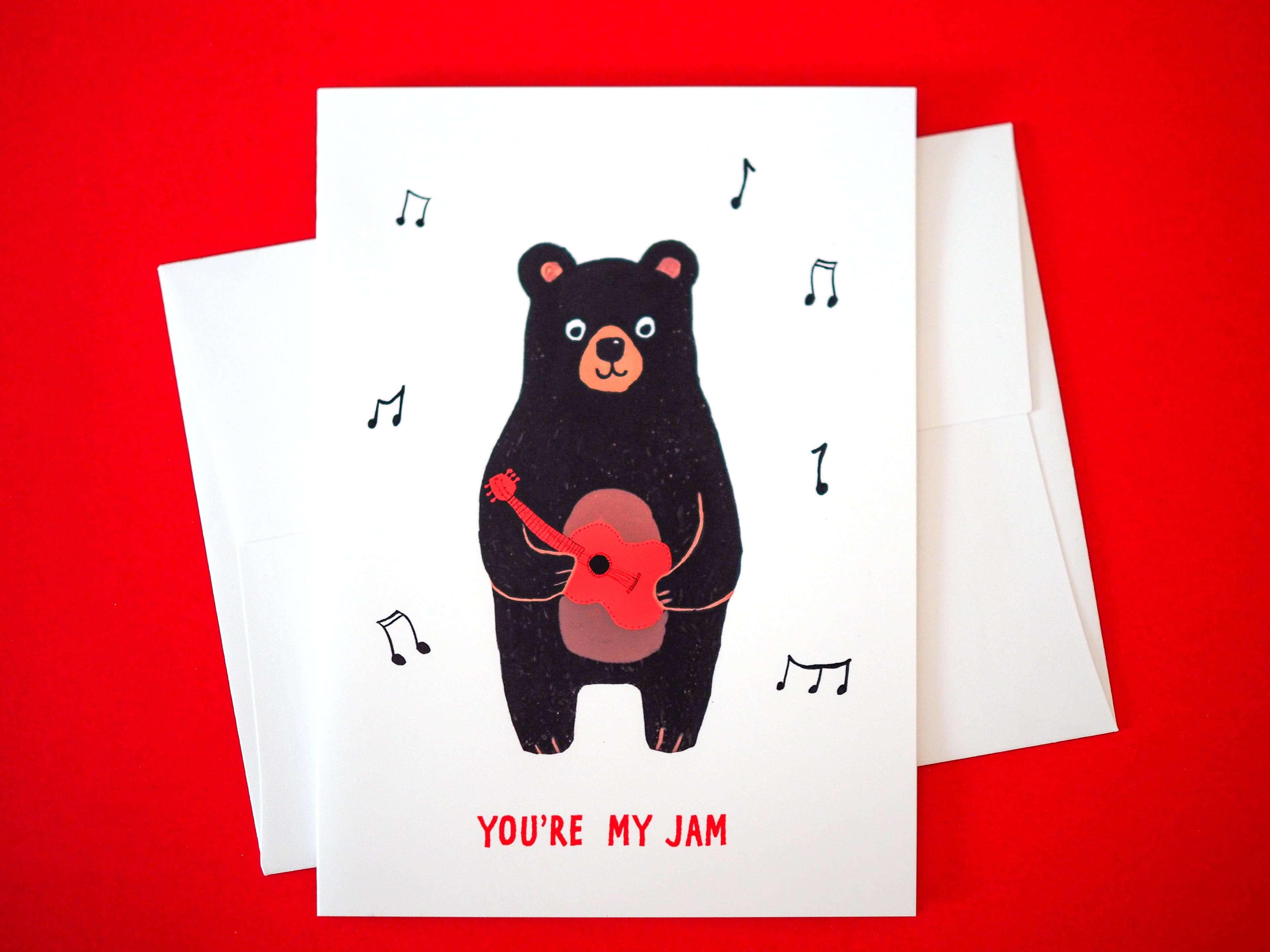 Greeting card with a bear holding a heart-shaped guitar and 'You're My Jam' text on a red background.